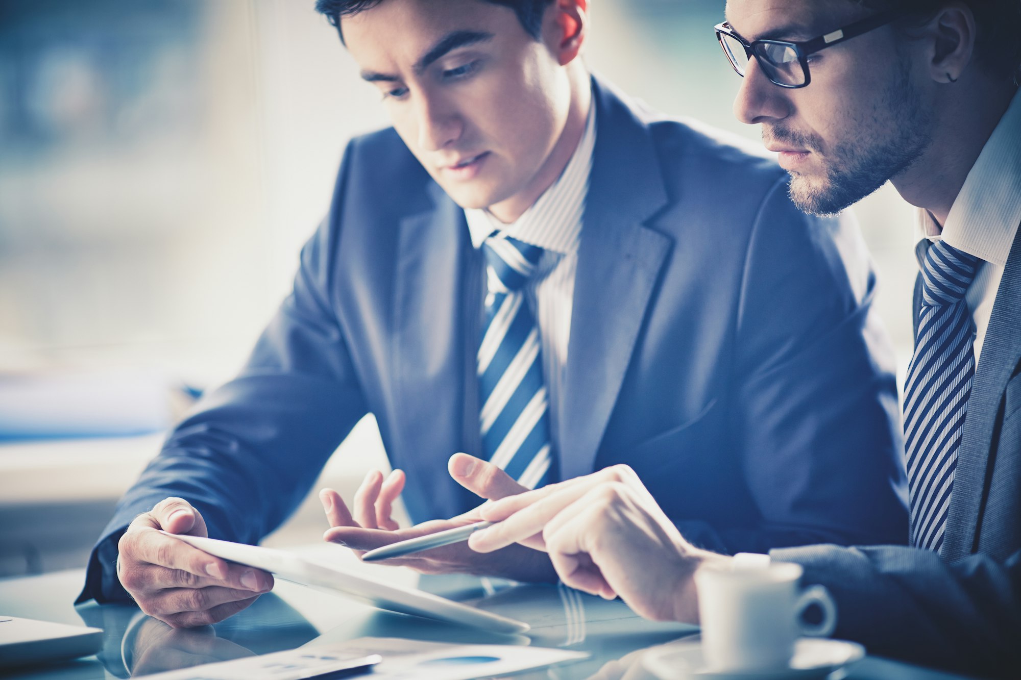 Close-up of two men looking at documents, depicting business consulting.